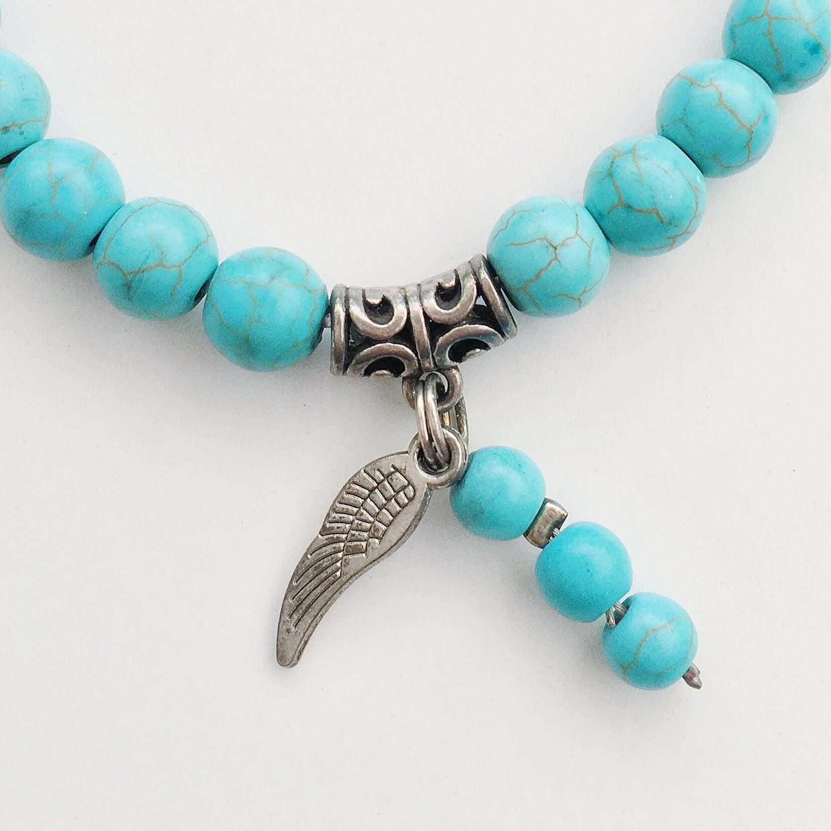 Detail view of beaded bracelet with matching 3 bead dangle and silver finish angel wing attached to silver bead.