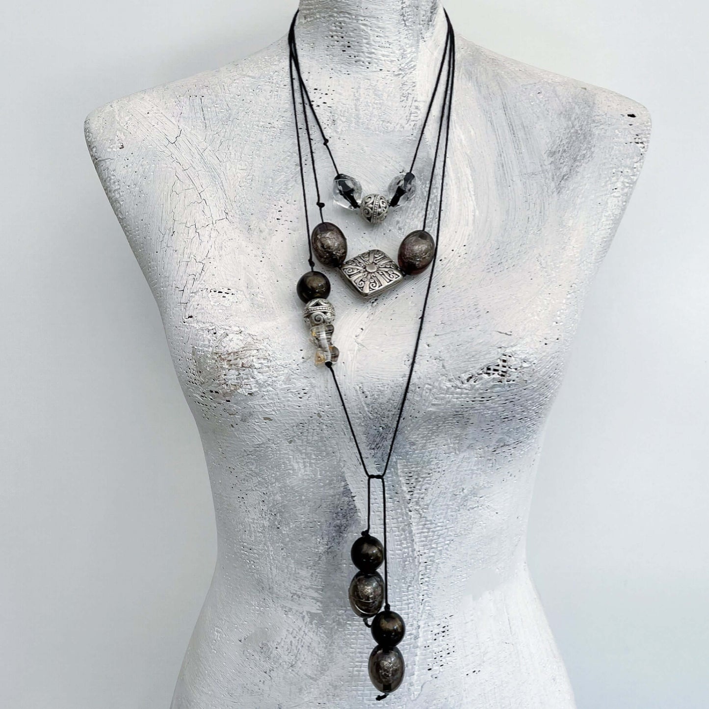 Front view of necklace shown wrapped around the neck in layers, beads in varying positions.