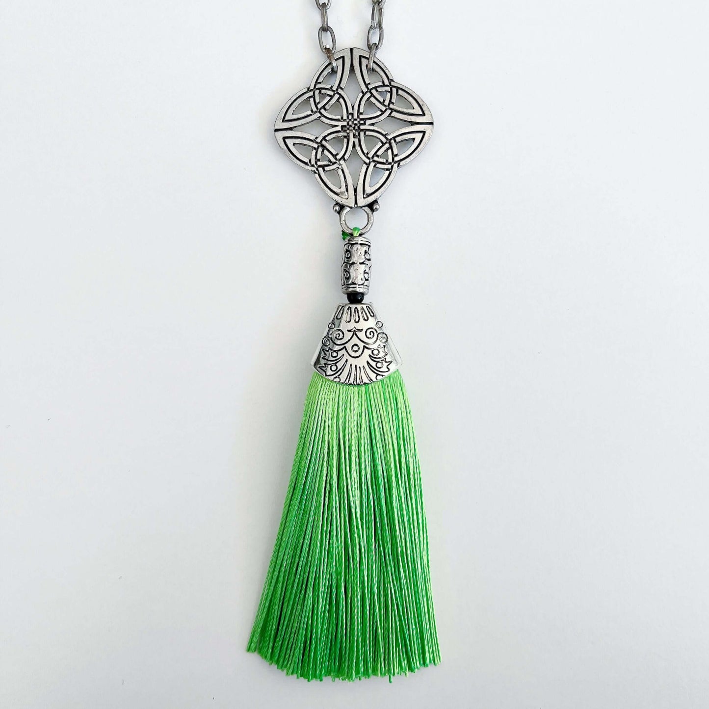 Detail view of the silver finish Celtic pendant, with green tassel on the end.