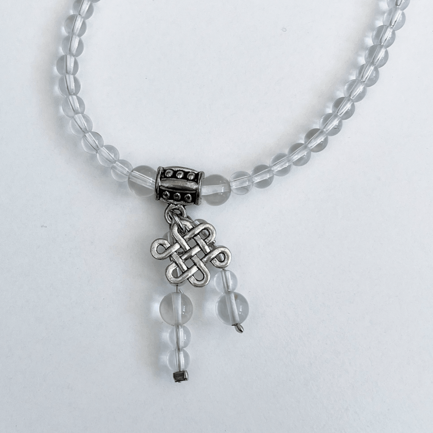 Detail view of necklace showing the Celtic knot charm and Clear Quartz dangling beads.