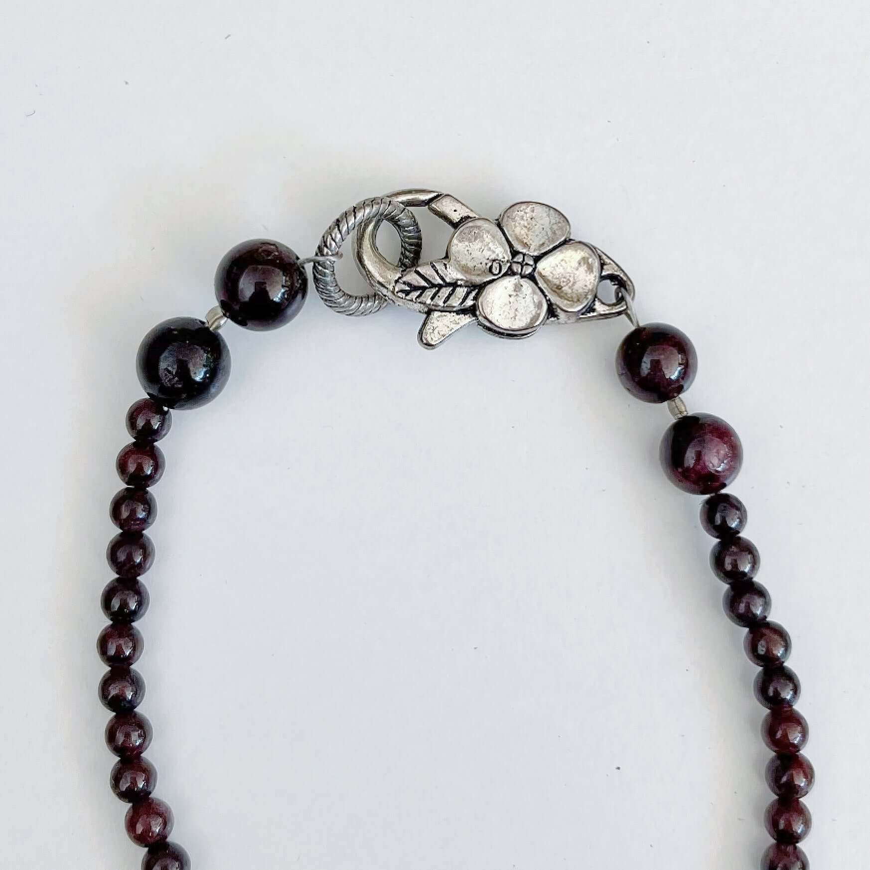 Detail view of the silver finish floral clasp, with Garnet beading at each side.