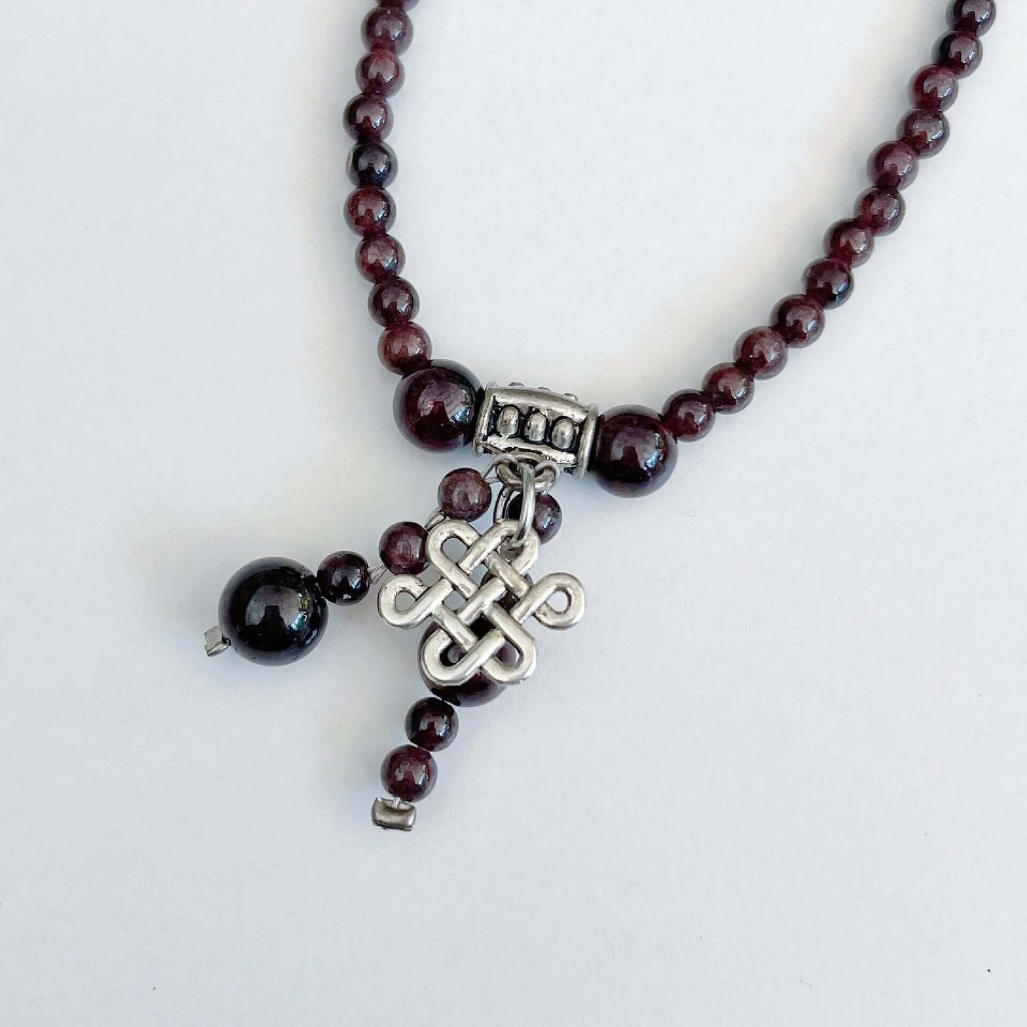 Detail view of necklace showing the Celtic knot charm and Garnet dangling beads.