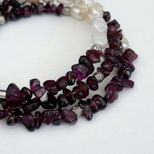 Detail view of bracelet, mixture of fresh water pearls, silver beads and garnet.