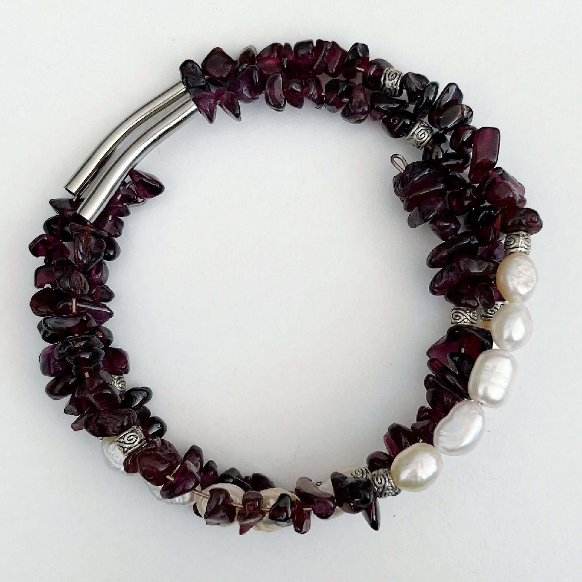 Top view of bracelet, showing long silver tubular bead in two places, between the tumbled garnet.