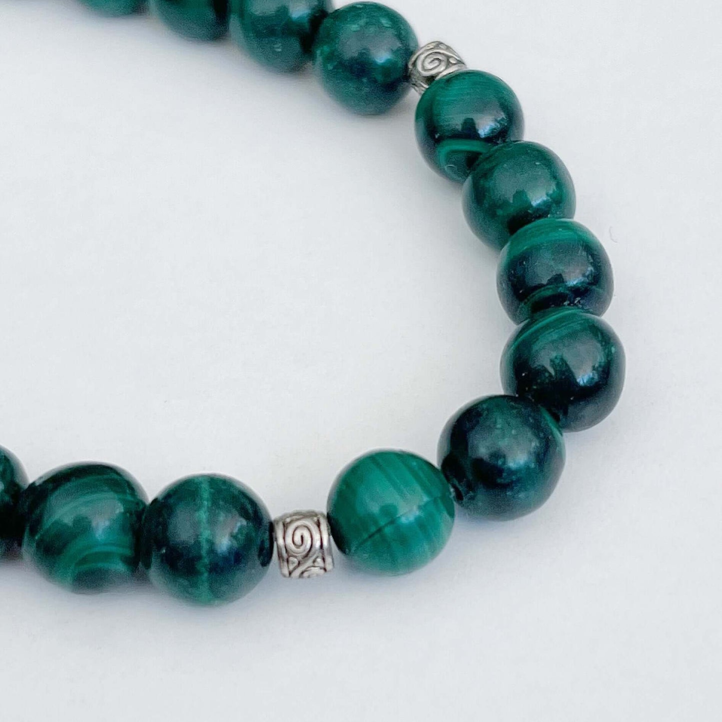 Detail view of elasticated bracelet, showing the individual beads, which have shades of deep green.