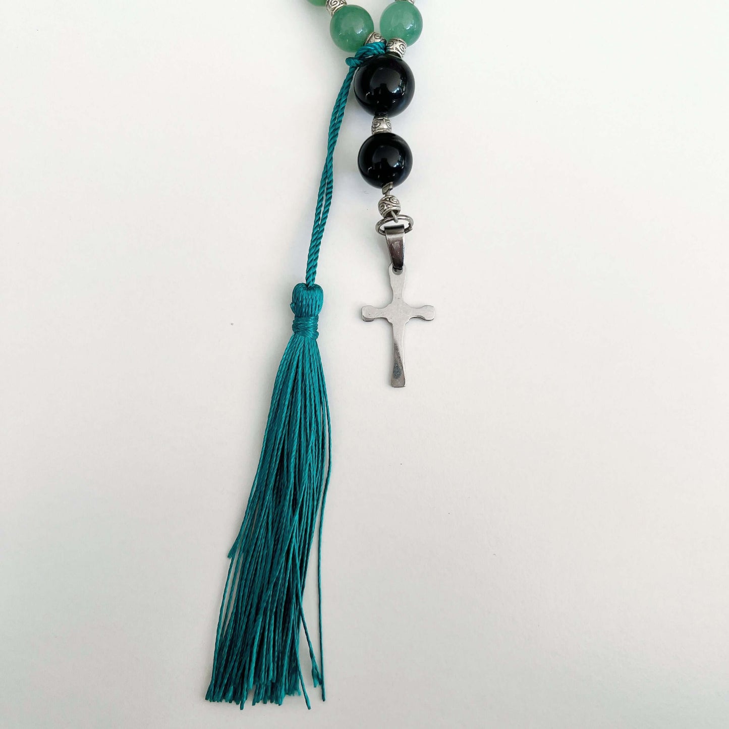 Detail view of prayer beads, Aventurine sections, with one Obsidian here and there. Cross and tassel at the bottom.