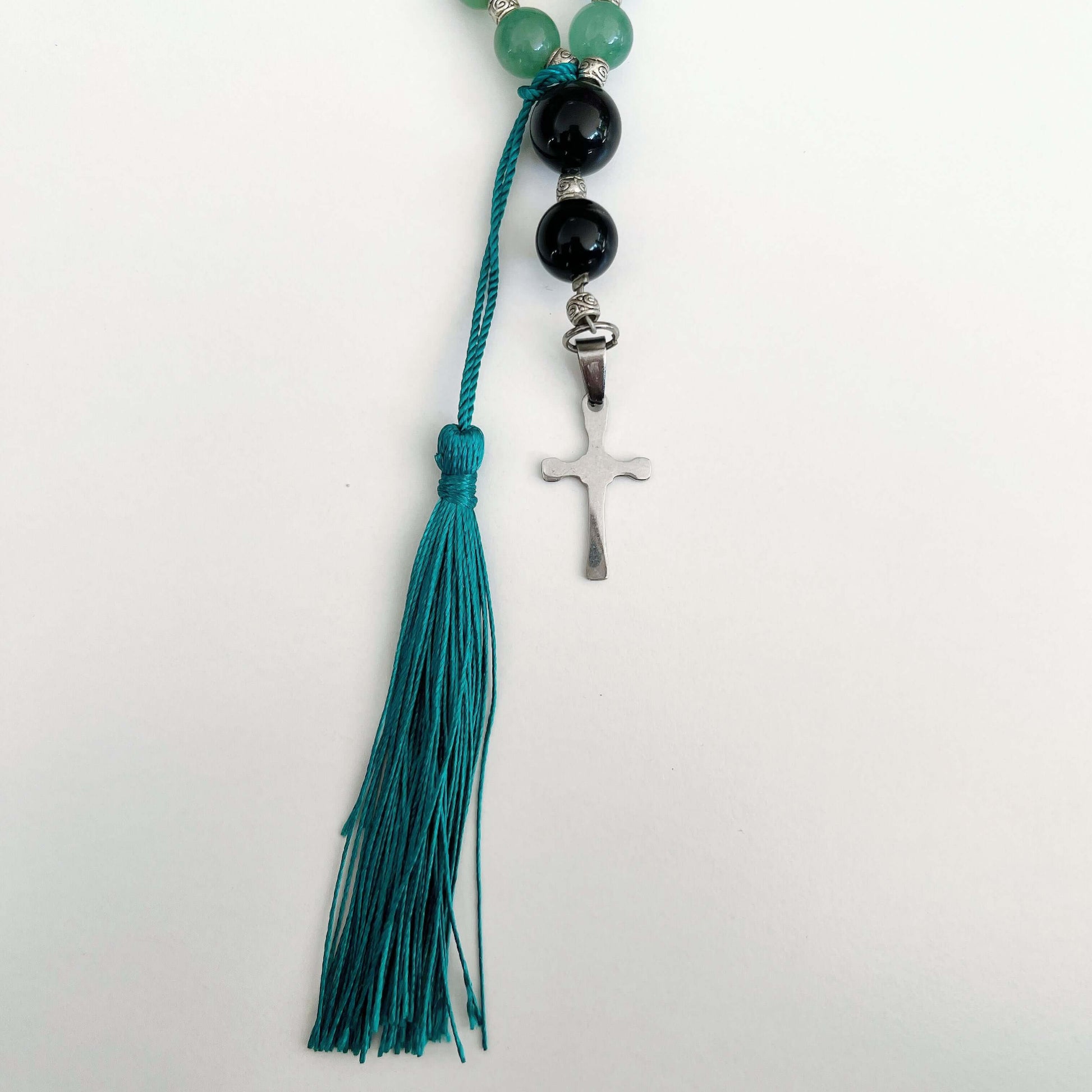Detail view of prayer beads, Aventurine sections, with one Obsidian here and there. Cross and tassel at the bottom.
