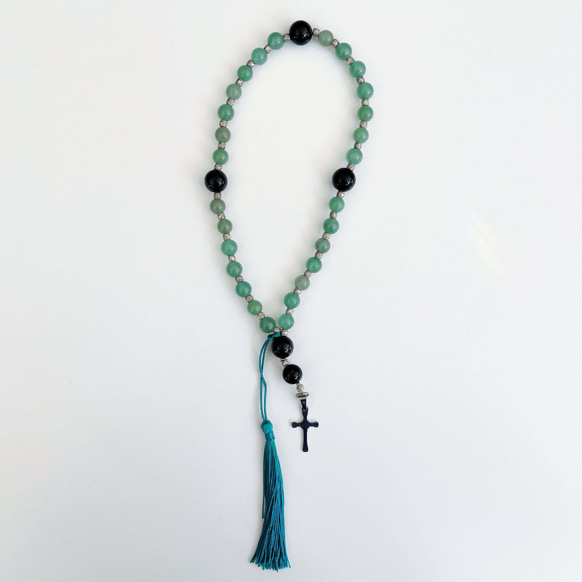 Top view of prayer beads, Aventurine sections, with one Obsidian here and there. Cross and tassel at the bottom.