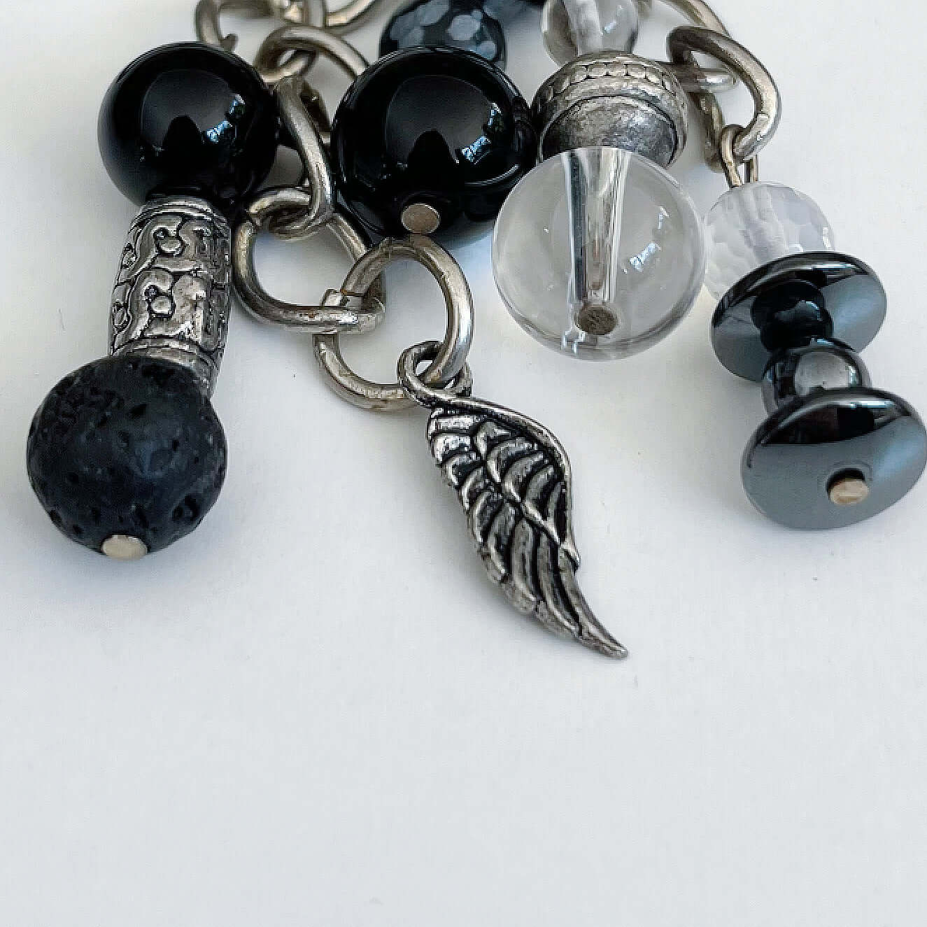 Detail view of keyring showing 5 dangling chains each with beads, and one with the angel wing charm.