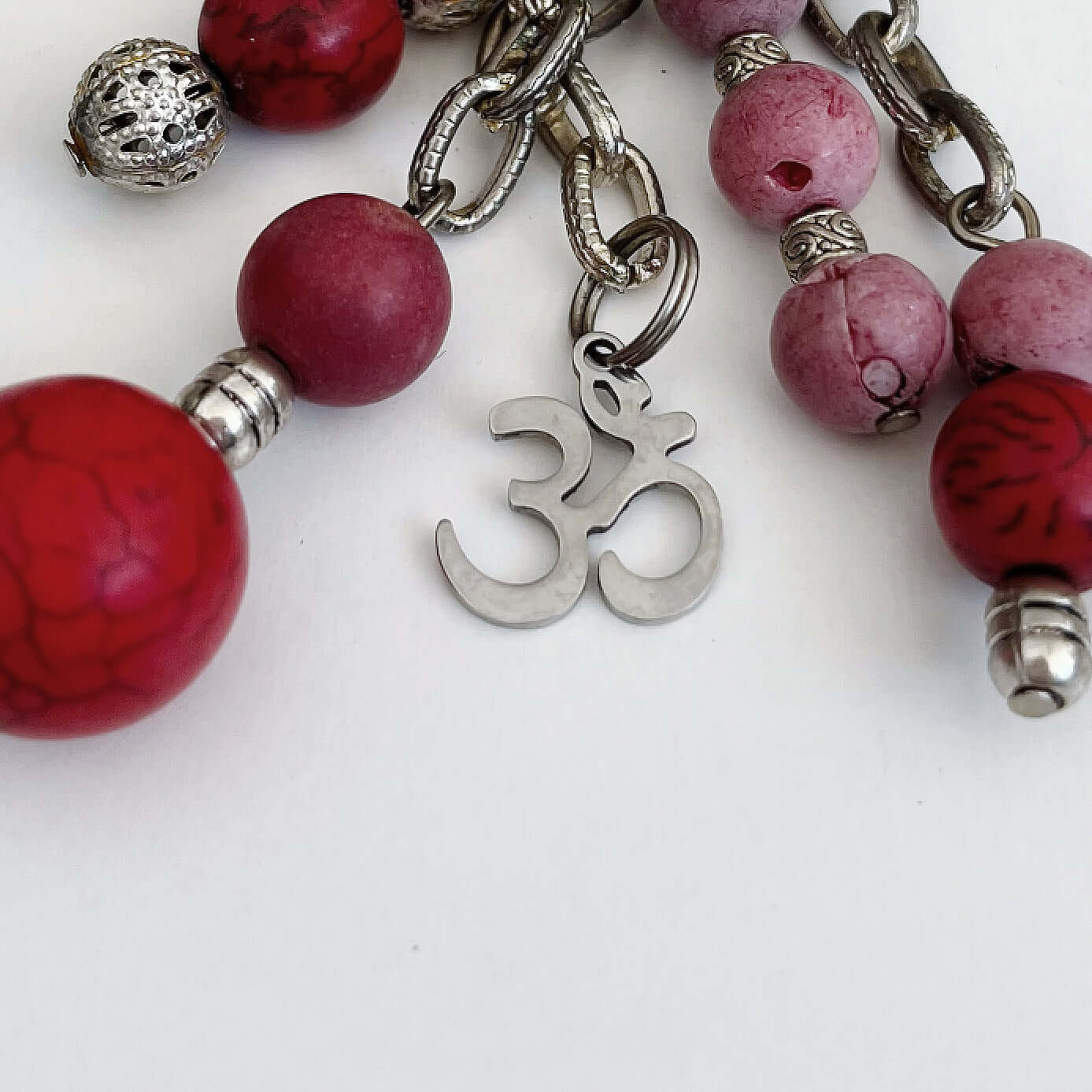 Detail view of keyring showing 5 dangling chains each with beads, and one with the Om sign charm.