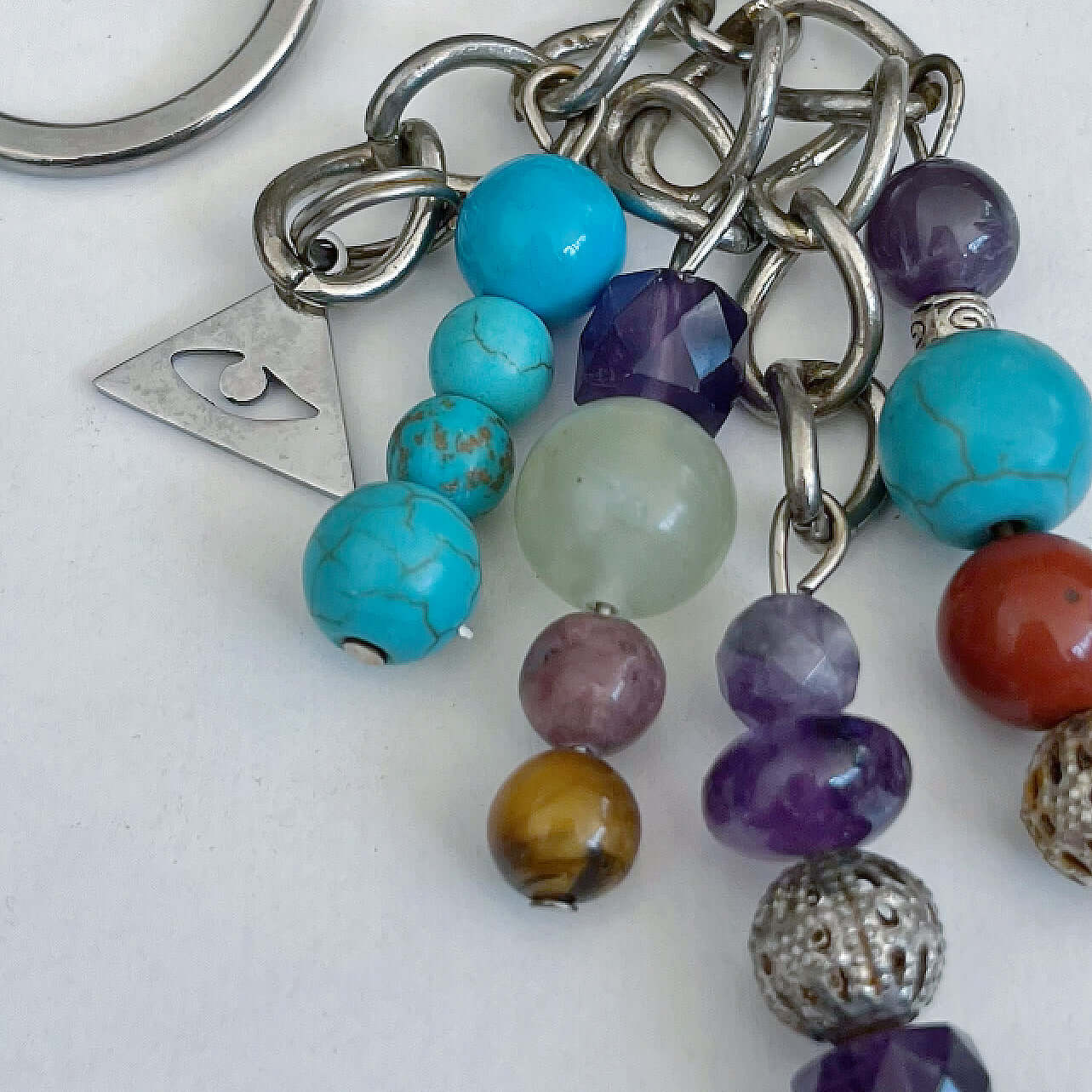 Detail view of keyring showing 5 dangling chains each with beads, and one with the Illuminati charm.