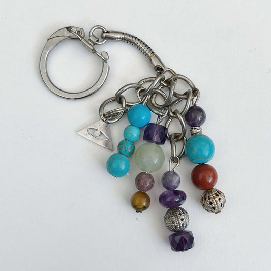 Top view of keyring showing 5 dangling chains each with beads, and one with the Illuminati charm.