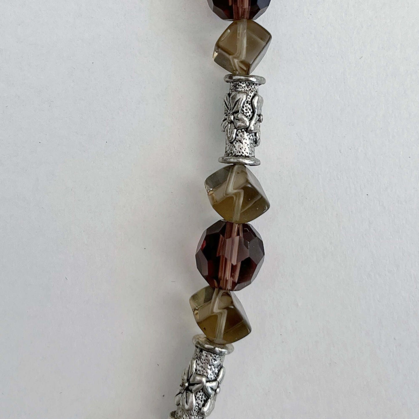 Detail view of the dusty grey lead crystal, Smokey Quartz, and silver finish floral patterned beads.