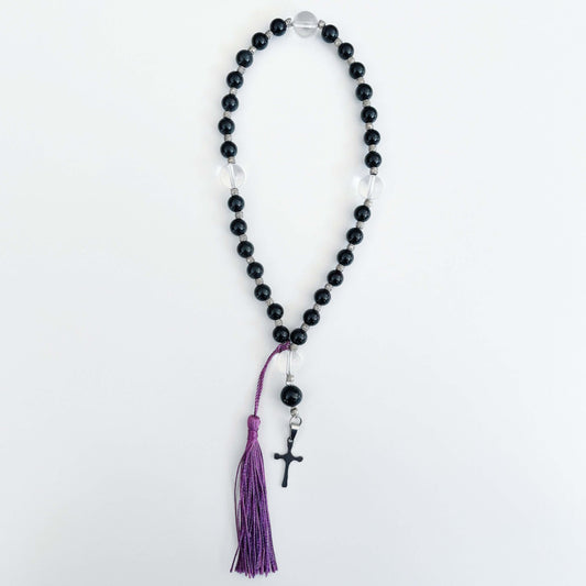 Top view of prayer beads, Obsidian sections, with one clear quartz here and there. Cross and tassel at the bottom.