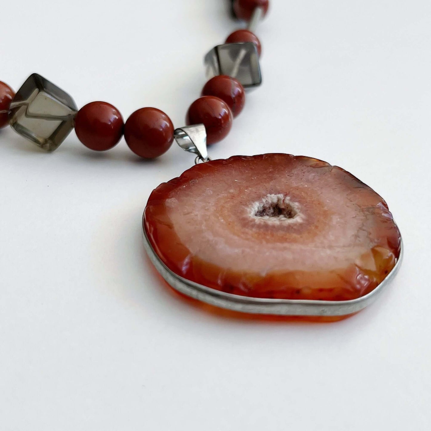 Detail view of the Orange Agate pendant, with Red Jasper and Smokey Quartz beads on either side.