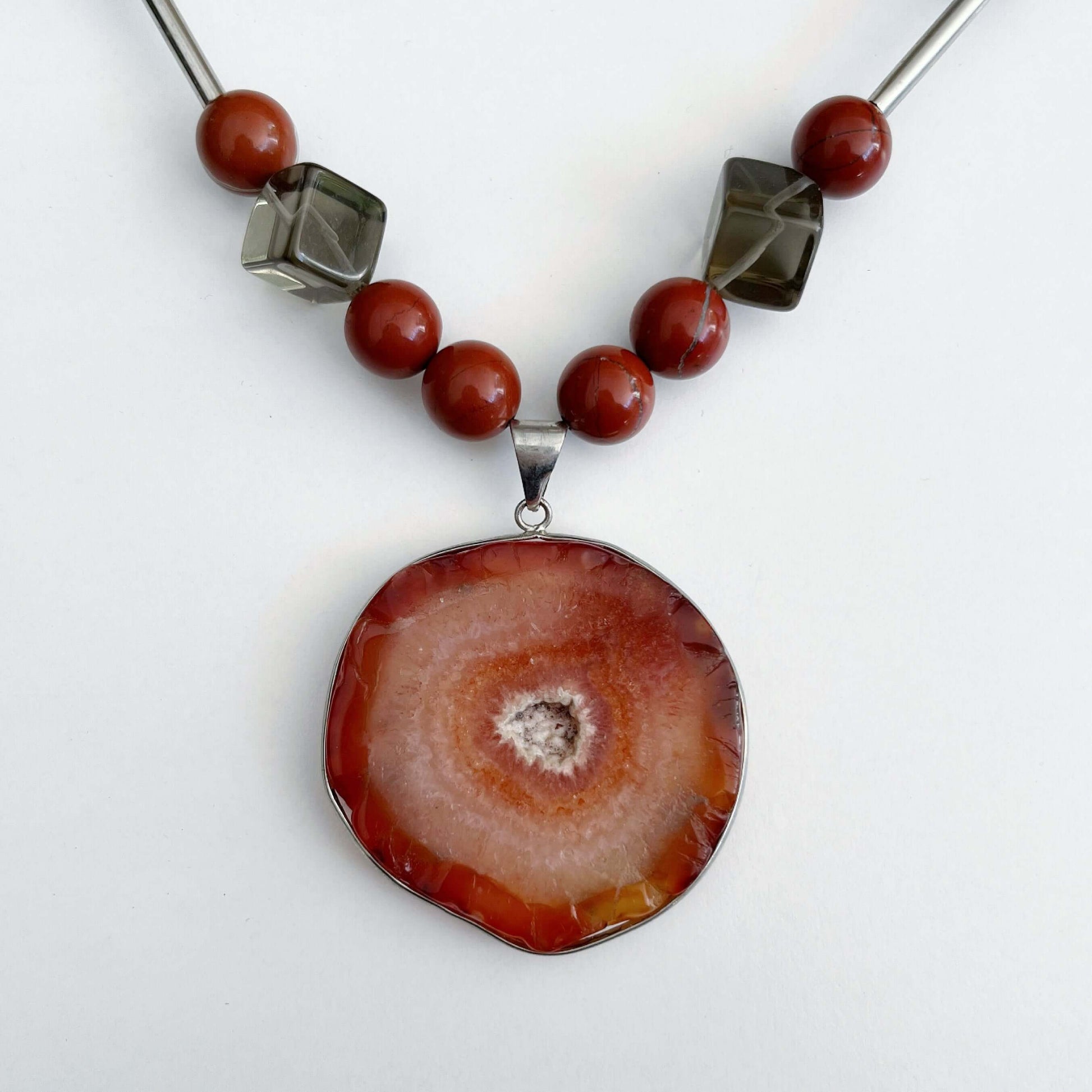 Detail view of the Orange Agate pendant, with Red Jasper and Smokey Quartz beads on either side.