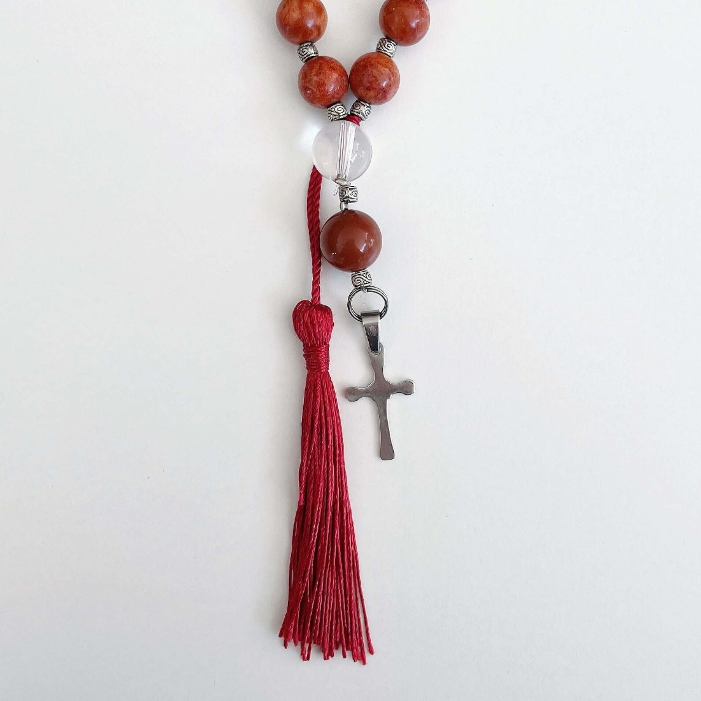 Detail view of prayer beads, Coral sections, with one Clear Quartz here and there. Cross and tassel at the bottom.