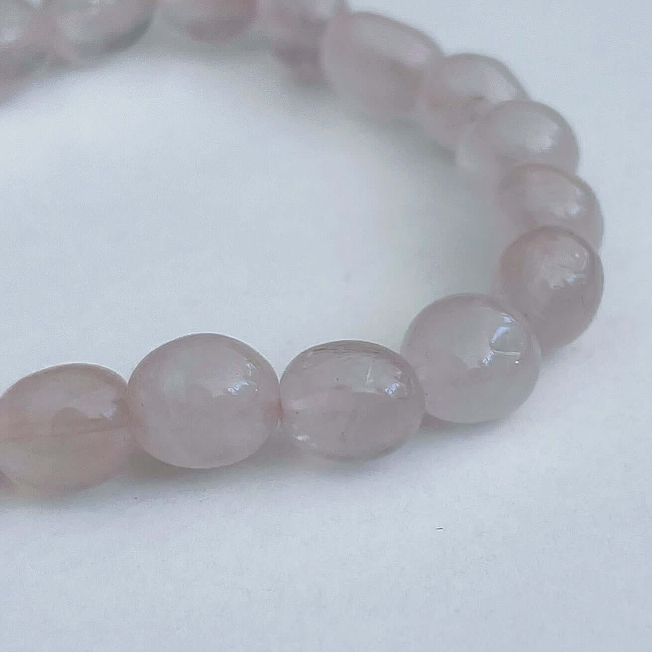 Detail view of elasticated bracelet, showing the individual beads, which have a soft pink coloring.