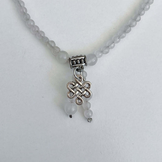 Detail view of necklace showing the Celtic knot charm and Rose Quartz dangling beads.