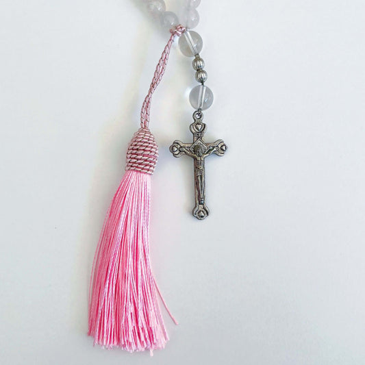 Detail view of prayer beads, Rose Quartz sections, with one Clear Quartz here and there. Cross and tassel at the bottom.
