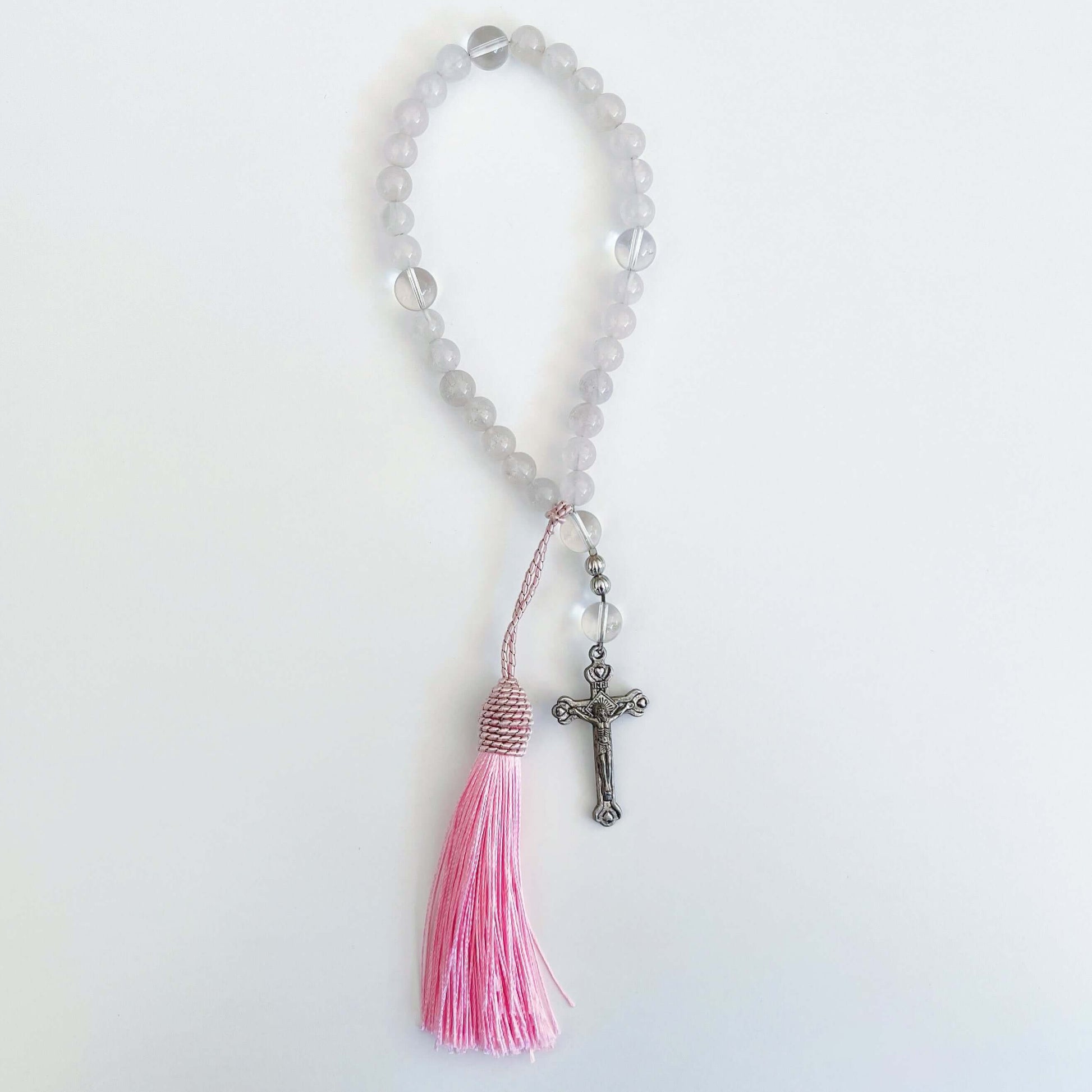 Top view of prayer beads, Rose Quartz sections, with one Clear Quartz here and there. Cross and tassel at the bottom.