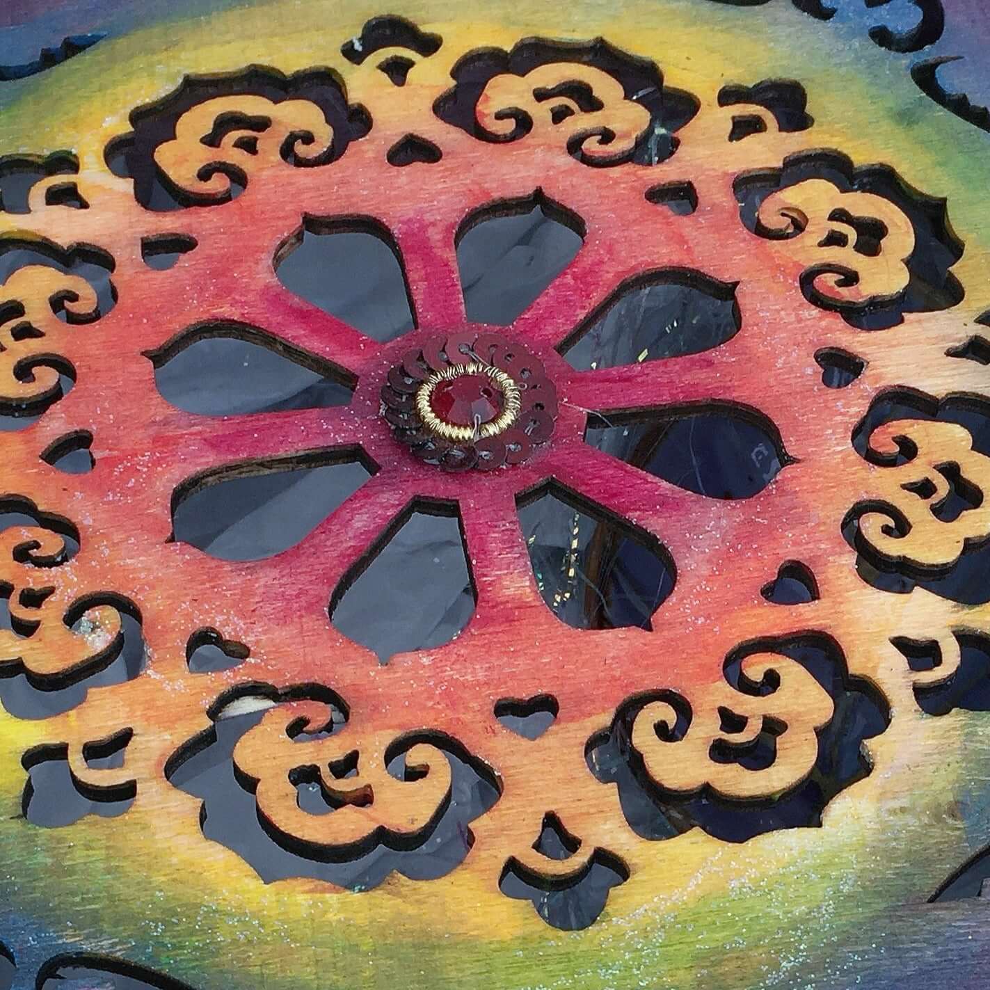 Detail view of painted lid, small red jewel in the center.