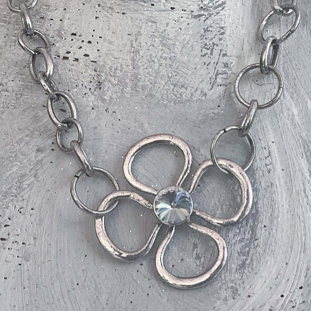 Closeup of daisy with single crystal in the center, strung with large silvery rings.