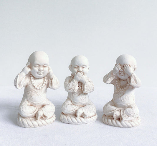 Front view of monks, all three in a row, natural off white colors, with ornate robes.