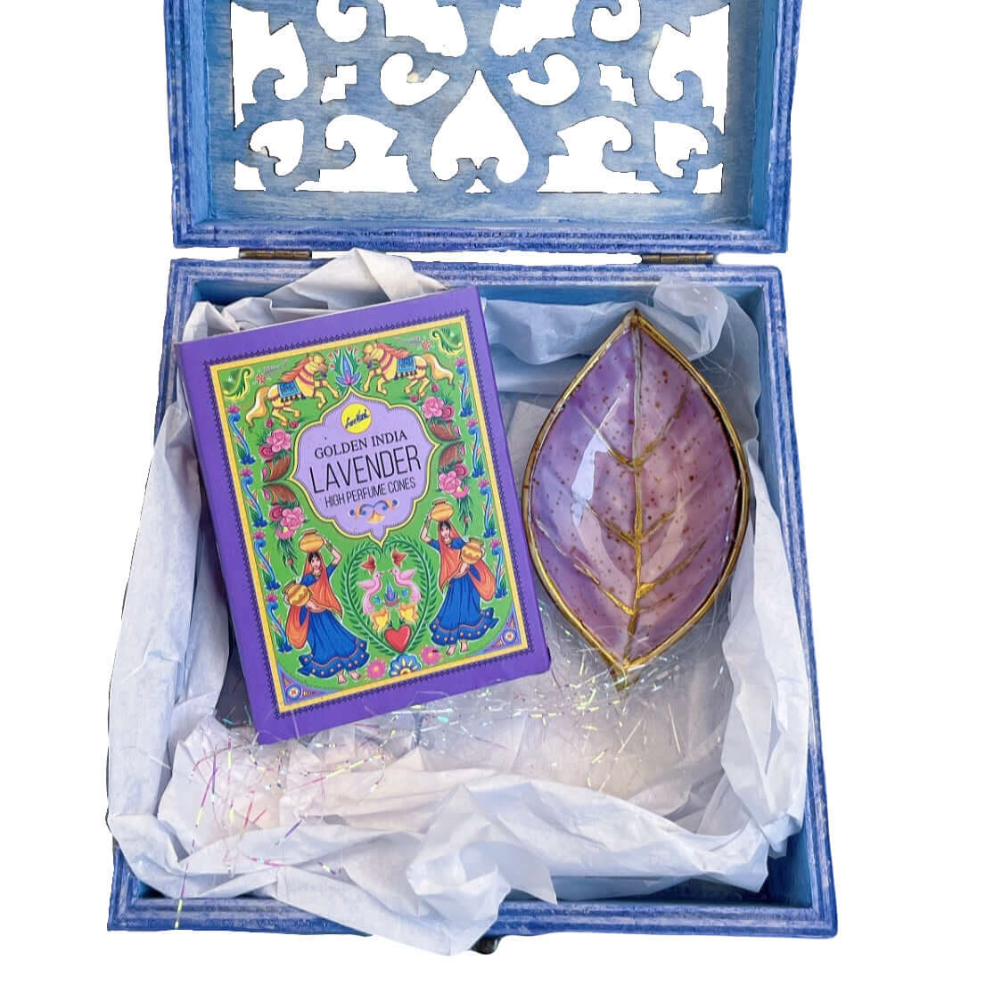 Contents view of incense and plum painted ceramic leaf, nestled in white tissue paper and tinsel.