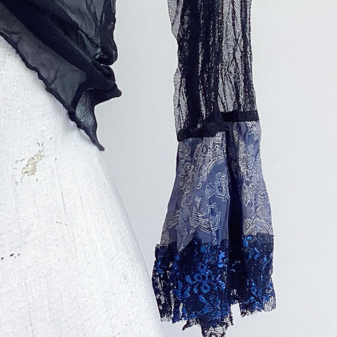 Close up view of tie top, black net sleeve, black and blue lace cuff.