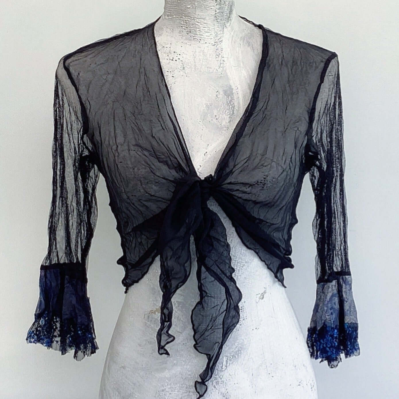 Front view of tie top, knot tied at the center, black chiffon fronts, black net sleeves, black and blue lace cuffs.