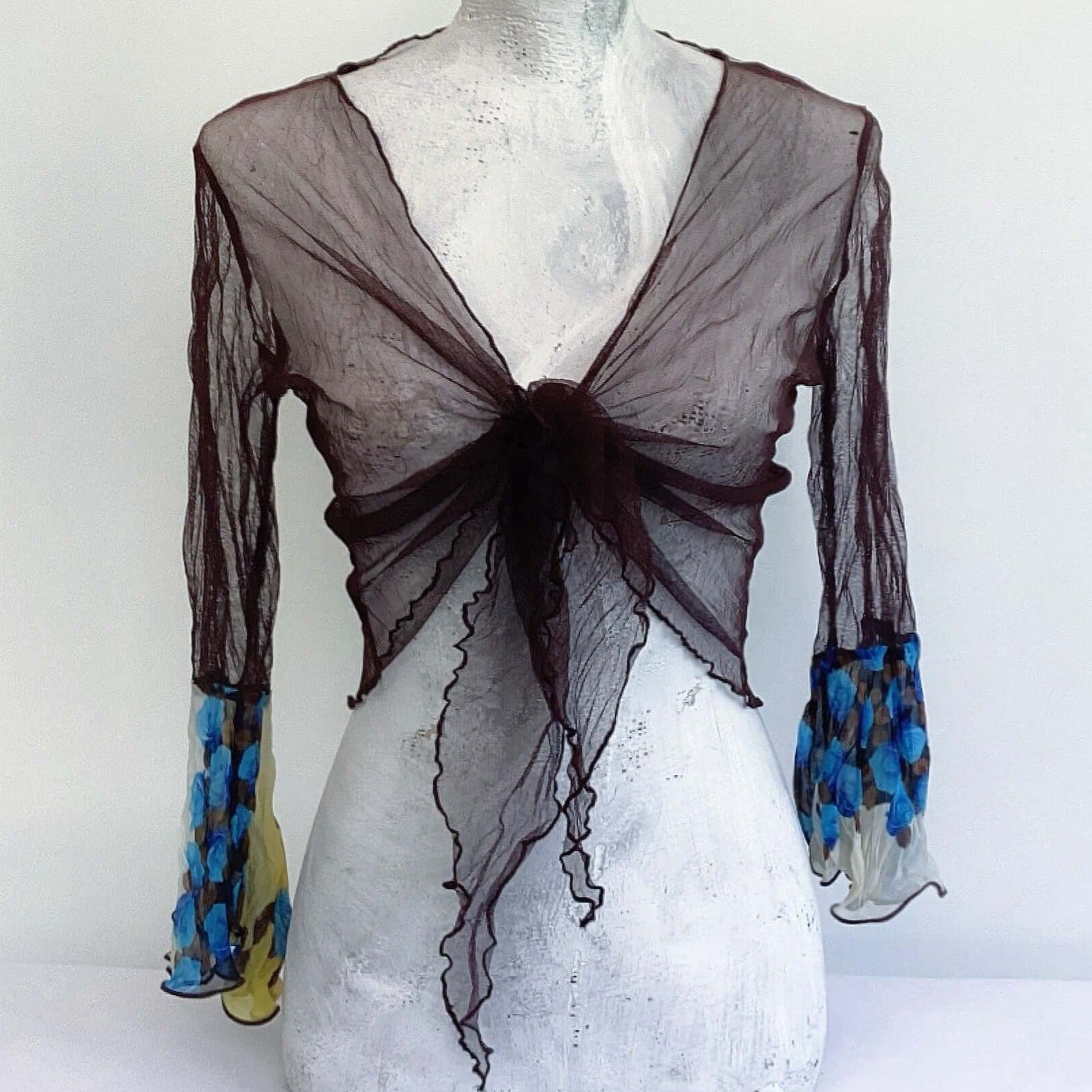 Front view of brown net tie top, tied in a knot at the front, with blue rose floral sleeves.