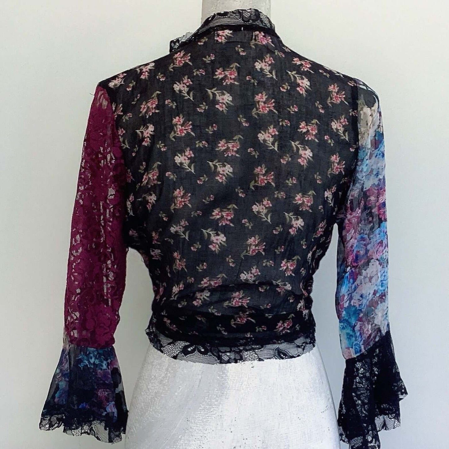 Back view of tie top, black floral cotton back, small pink flowers, floral chiffon sleeve right, plum lace sleeve left.