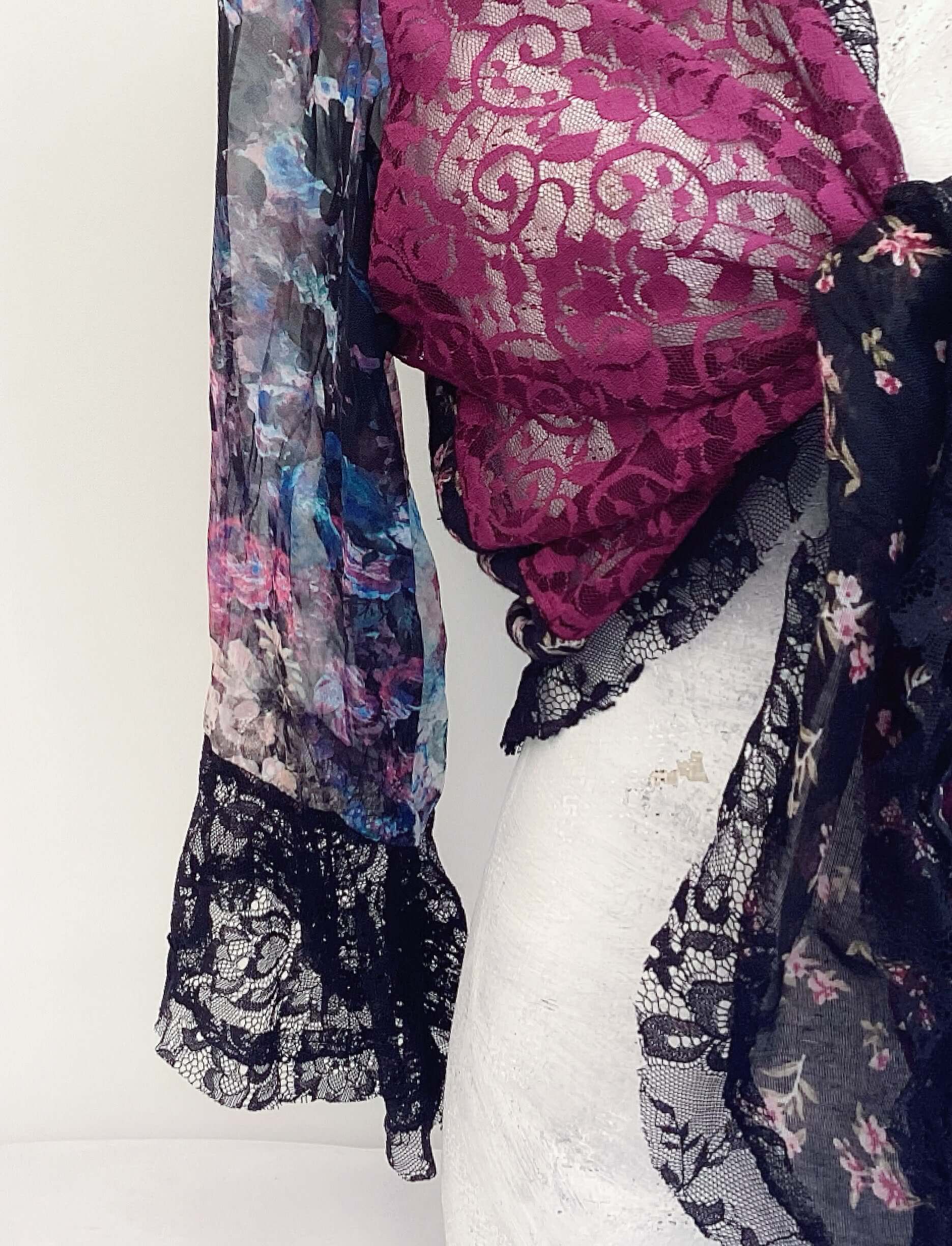 Close up view of left side plum lace front with floral chiffon sleeve, black lace on the cuff.