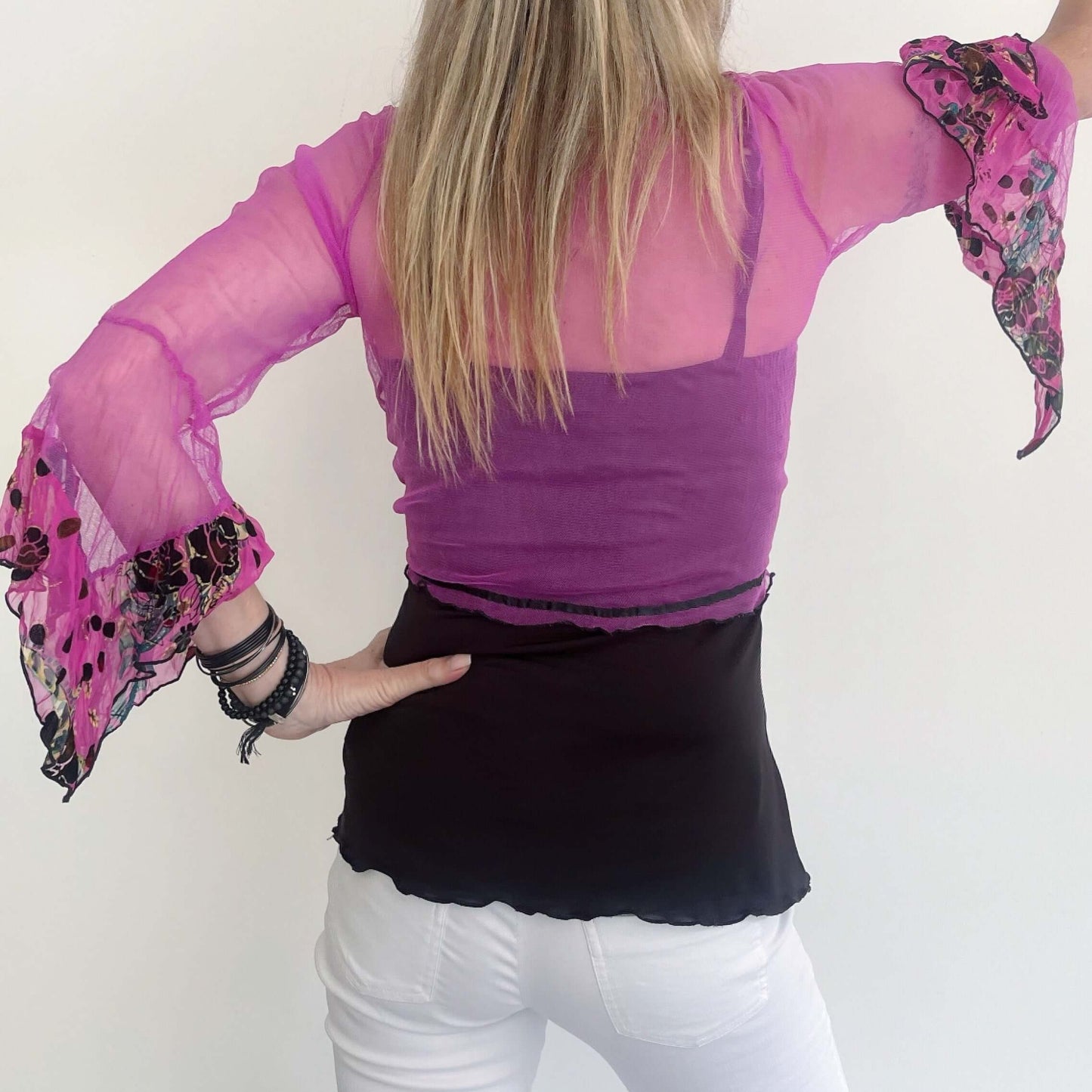 Back view of fuchsia net tie top, black rolled hem, pink flocked printed chiffon on sleeve frills, black ribbon along hem.