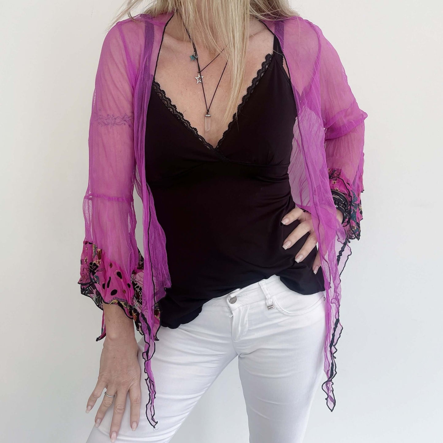 Front view fuchsia net tie top, worn loose, black roll hem, pink flocked chiffon on sleeve frills, black ribbon along hem.