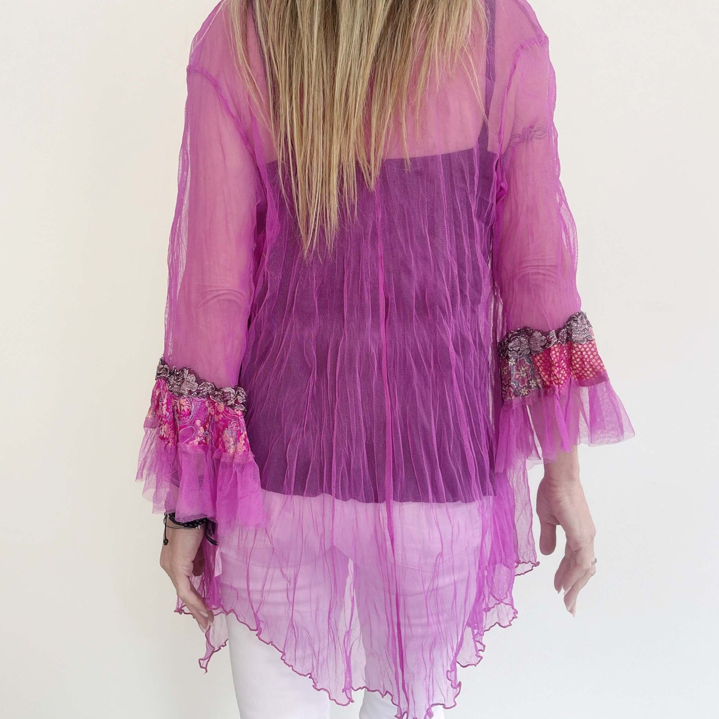 Back view of fuchsia jacket worn loose, model's arms by her sides. Seam at center.