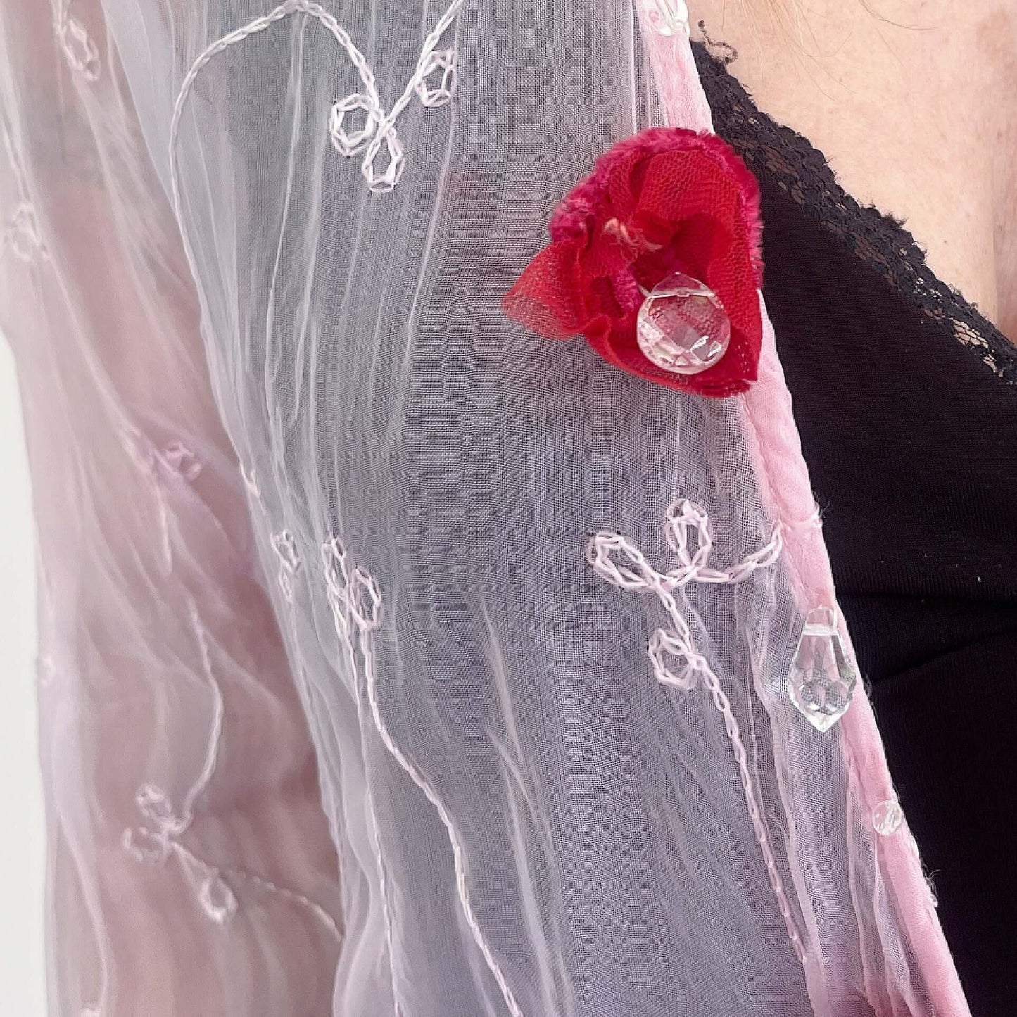 Detail view of tie top with cerise velvet trim on hem, and matching velvet roses and beadwork along opening, tied loosely.