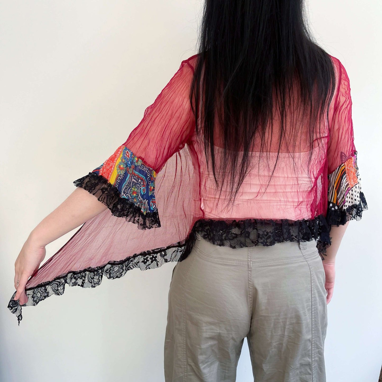 Front view maroon mesh top tied at center, printed chiffon sunset hues on sleeve frill, black lace edging on frill and hem.