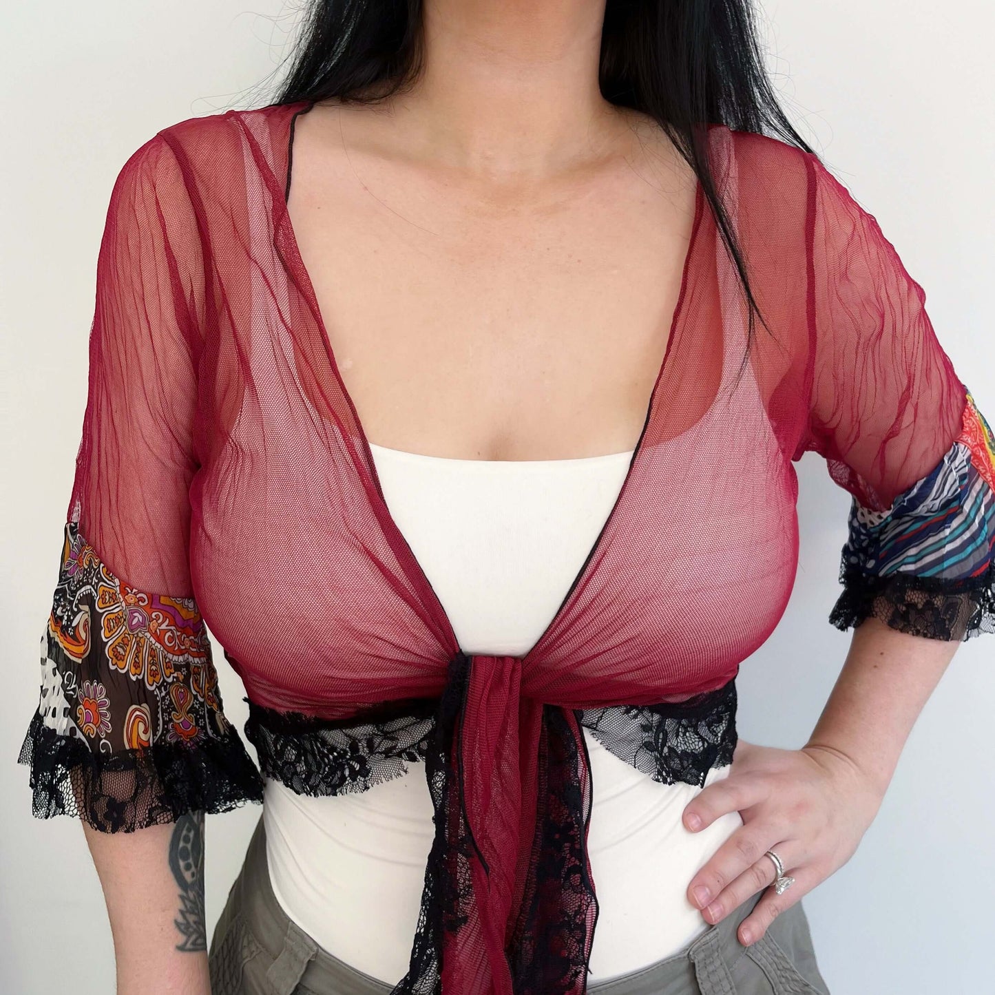 Front view maroon mesh top tied at center, printed chiffon sunset hues on sleeve frill, black lace edging on frill and hem.