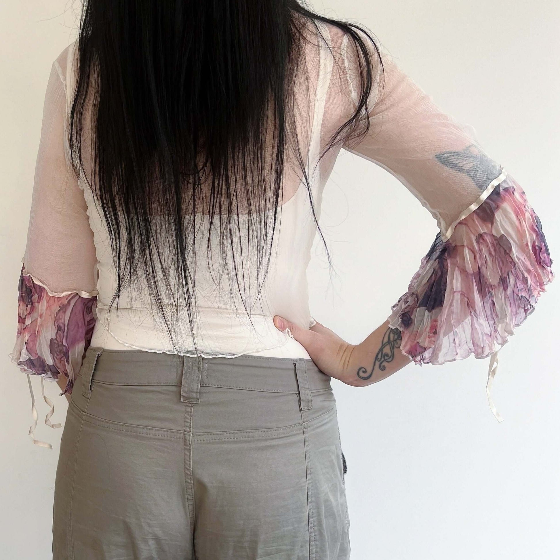 Back view of cream net tie top, with watercolor earthy toned printed chiffon sleeve frill, worn loose.