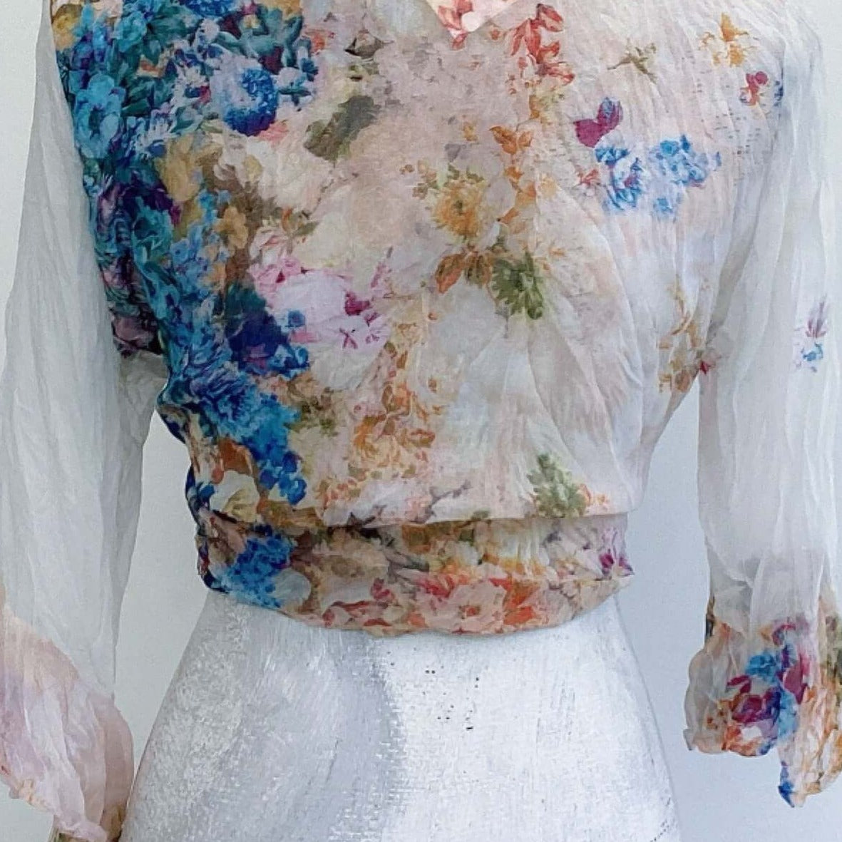 Back view of tie top, showing bright watercolor floral chiffon. both sleeves much paler, with flowers here and there.