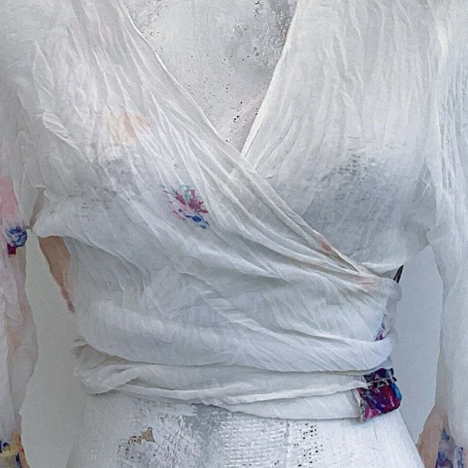 Front view of off white watercolor floral chiffon tie top, crossed over, pale flowers here and there.