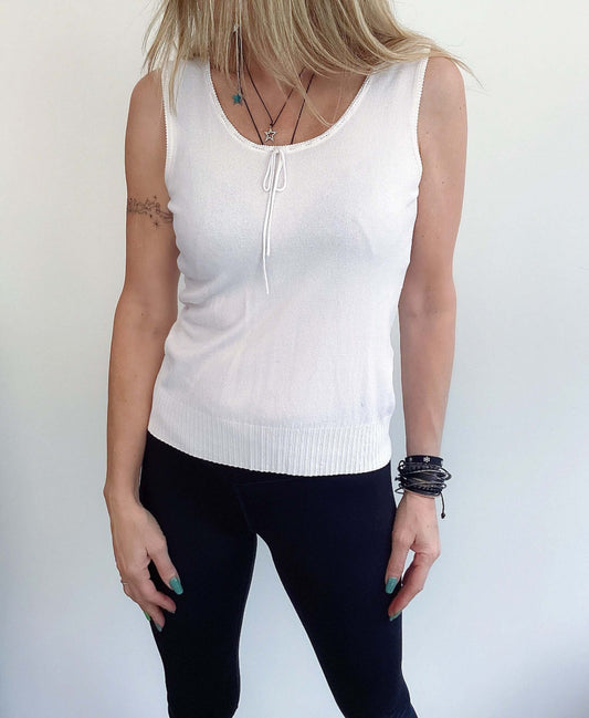 Front view of sleeveless top, scooped neck with string tie, hip length, ribbed at the bottom.