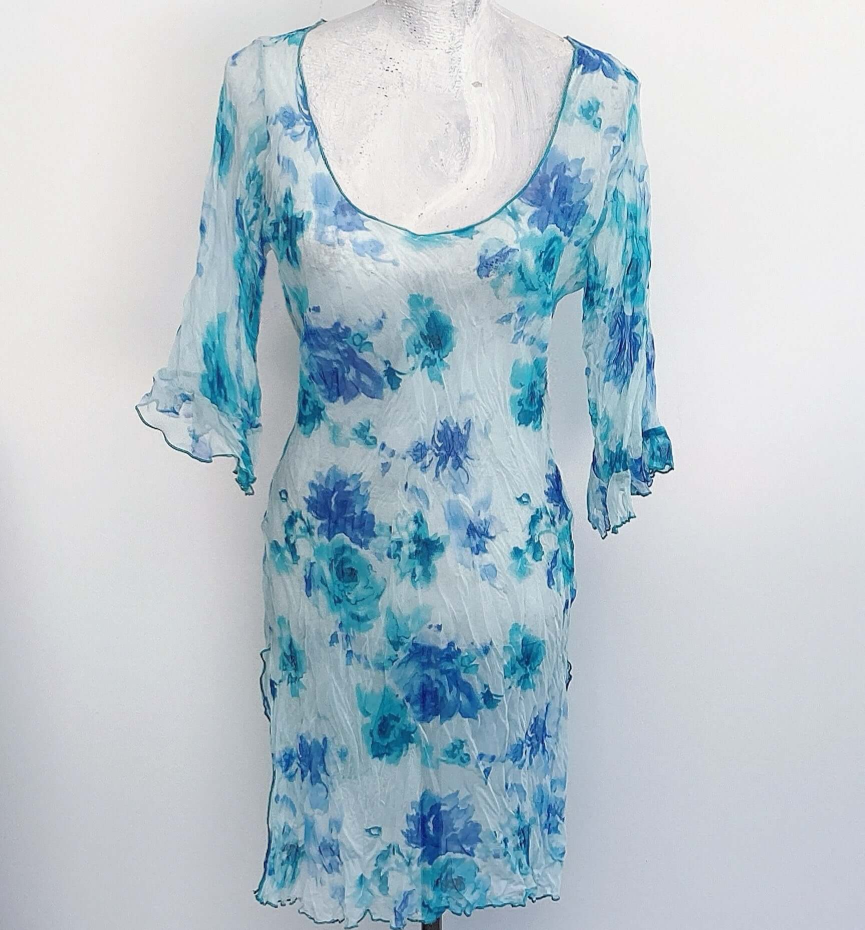 Front view of long chiffon top, three quarter sleeve with frill, wide scooped neck, rolled hems on neck, hem and slits.