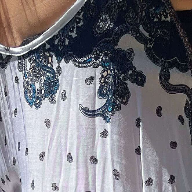 Detail view of dress, basic white with small black print motif all over, with bolder indian pattern at the top of dress.