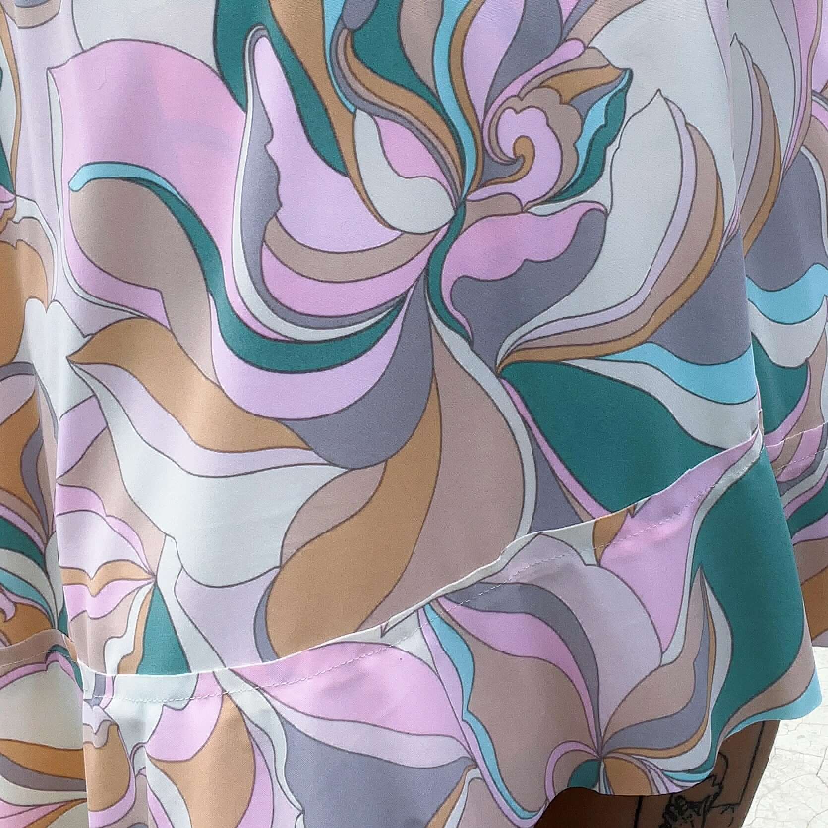 Detail view of the bold pastel print of orchids in teal, peach, pale yellow, turquoise, and pink.