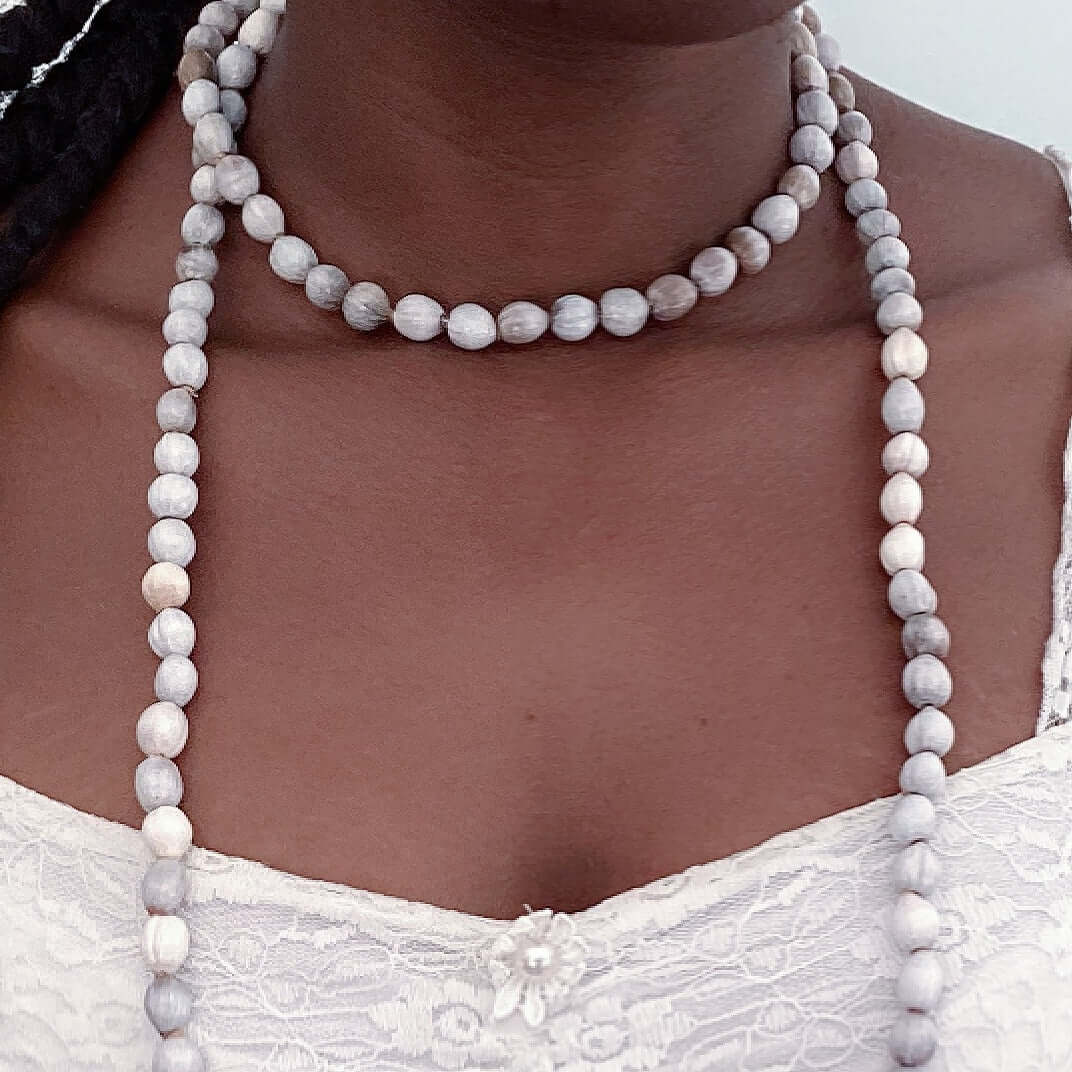 Detail view of imfibinga bead necklace worn double wrapped around the neck.